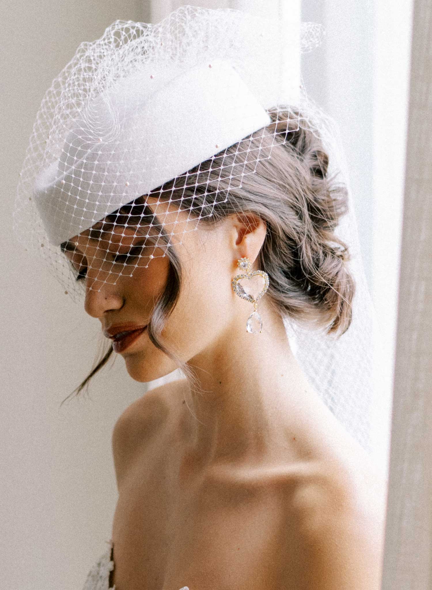 Bridal pillbox hat with pearl adorned birdcage veil and bow